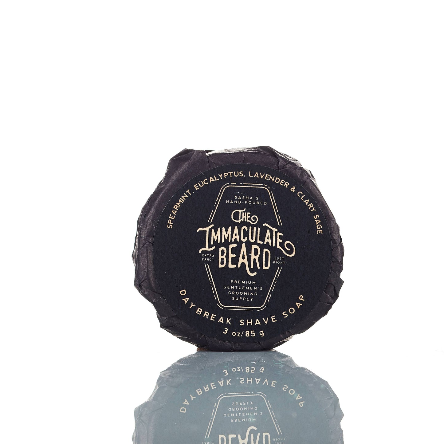 The Immaculate Beard shave soap puck in a round container, showing the creamy soap surface and textured packaging.