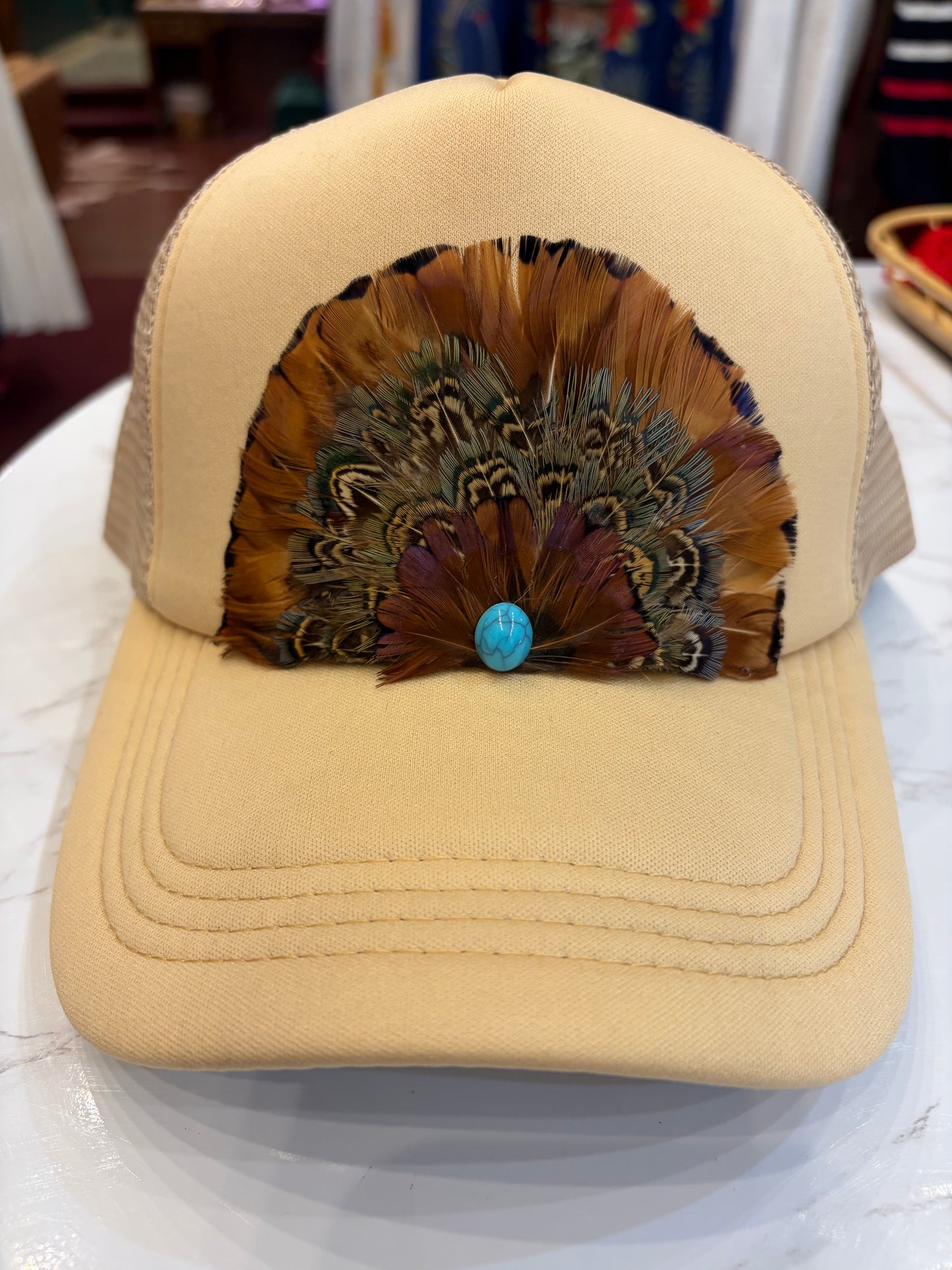 Queen Gypsy feather trucker hat with mesh back and curved brim, stylish casual headwear for outdoor wear.