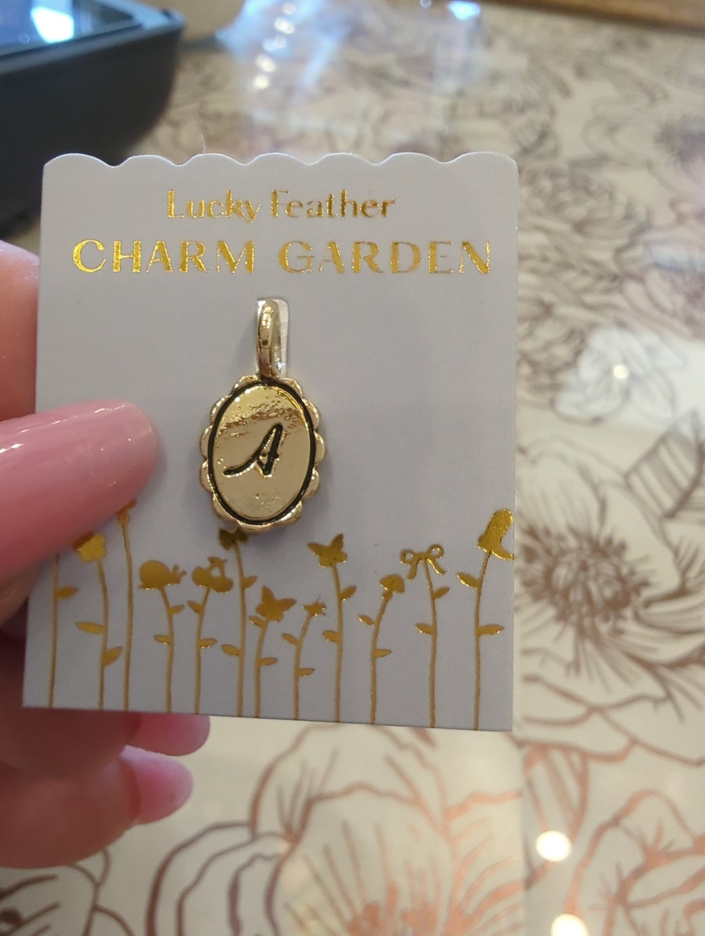 Gold initial charm with the letter A from Lucky Feather's Charm Garden collection, featuring intricate design on a silver charm.