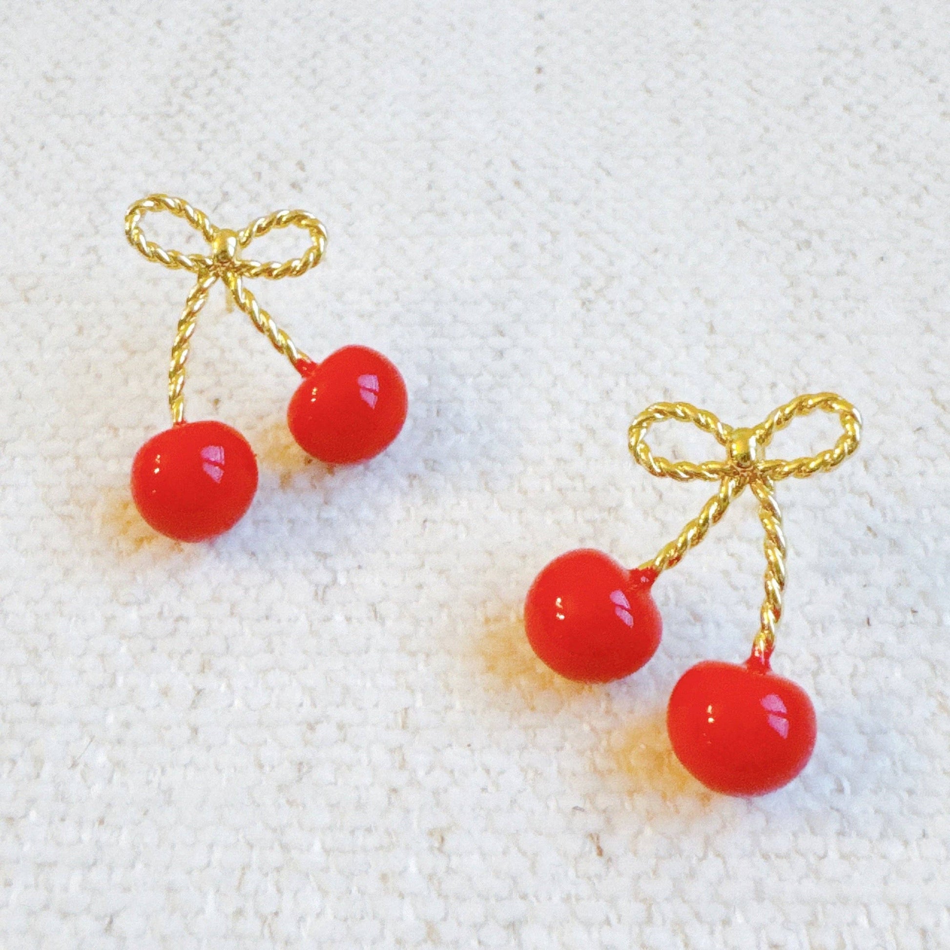 Ellison+Young bow and cherry earrings featuring gold-tone metal with red cherry accents and bow design for a playful accessory.