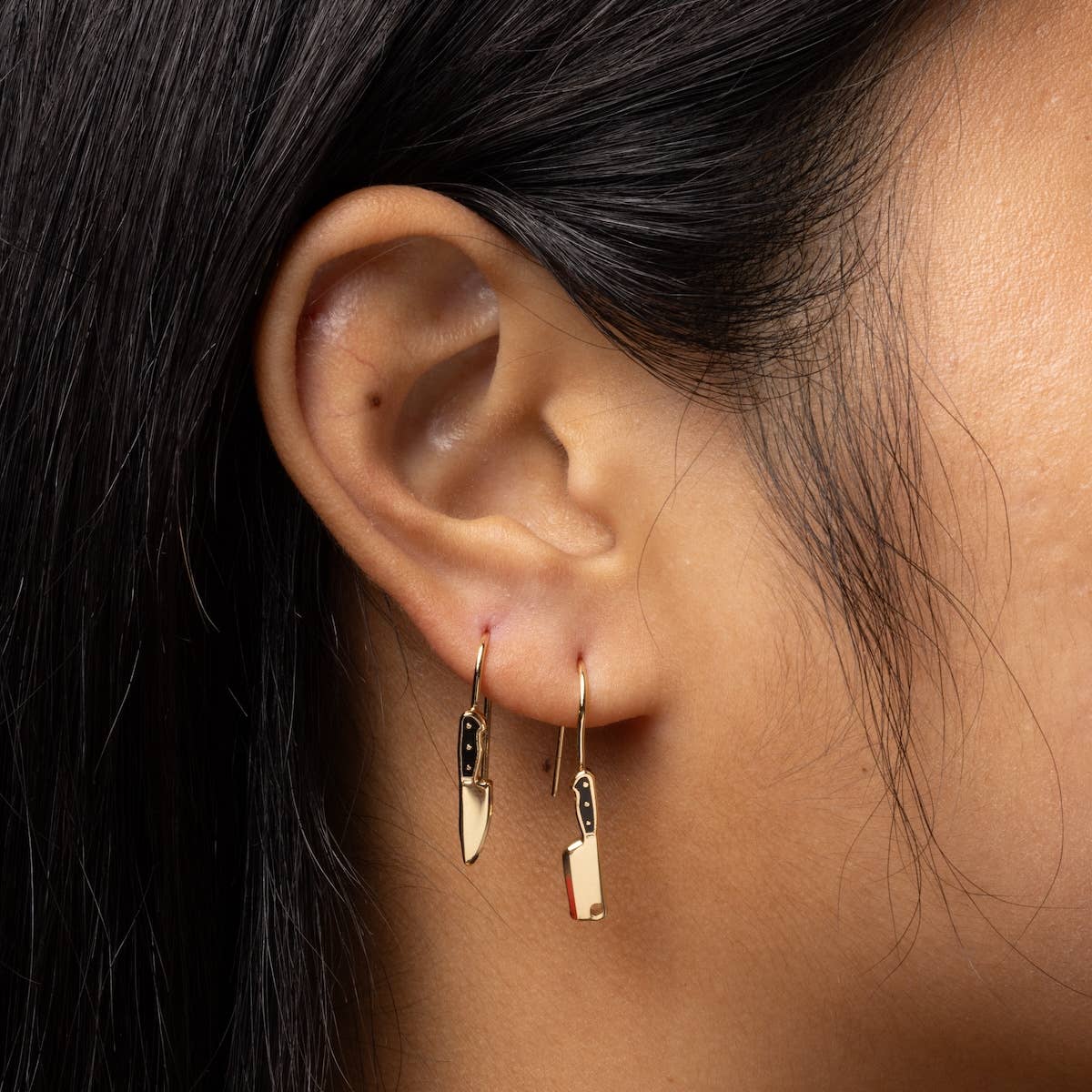 Yellow Owl Workshop chef's knife and cleaver earrings featuring detailed metal cutout designs on silver-colored earrings.