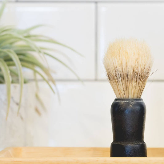 The Immaculate Beard shaving brush with natural bristles and a sleek handle for a smooth shaving experience.