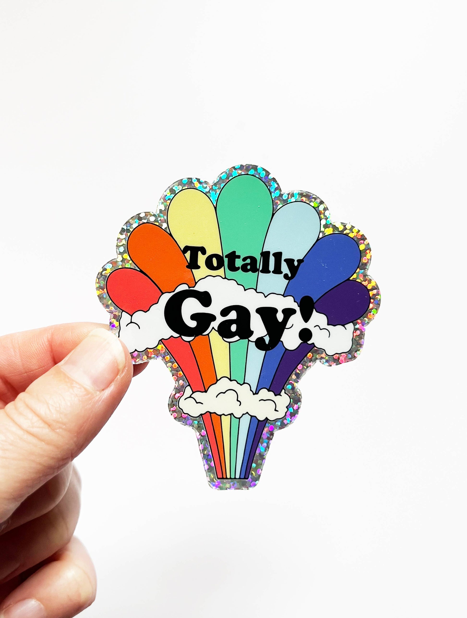 Colorful rainbow glitter sticker from The Coin Laundry with fun "Totally Gay" design, perfect for decorating notebooks or laptops.