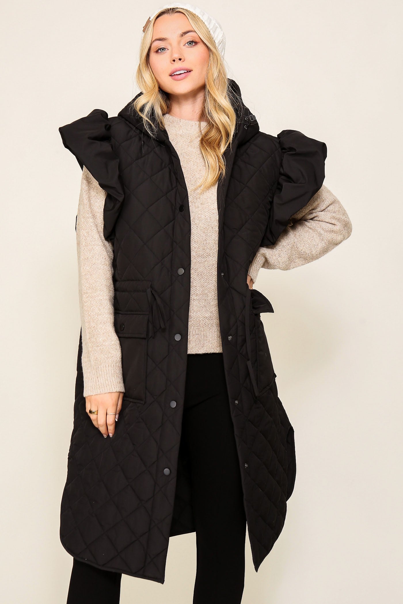 A Sparkling Mess puffer vest with ruffled cap sleeves, featuring a quilted design and a stand-up collar on a neutral background.