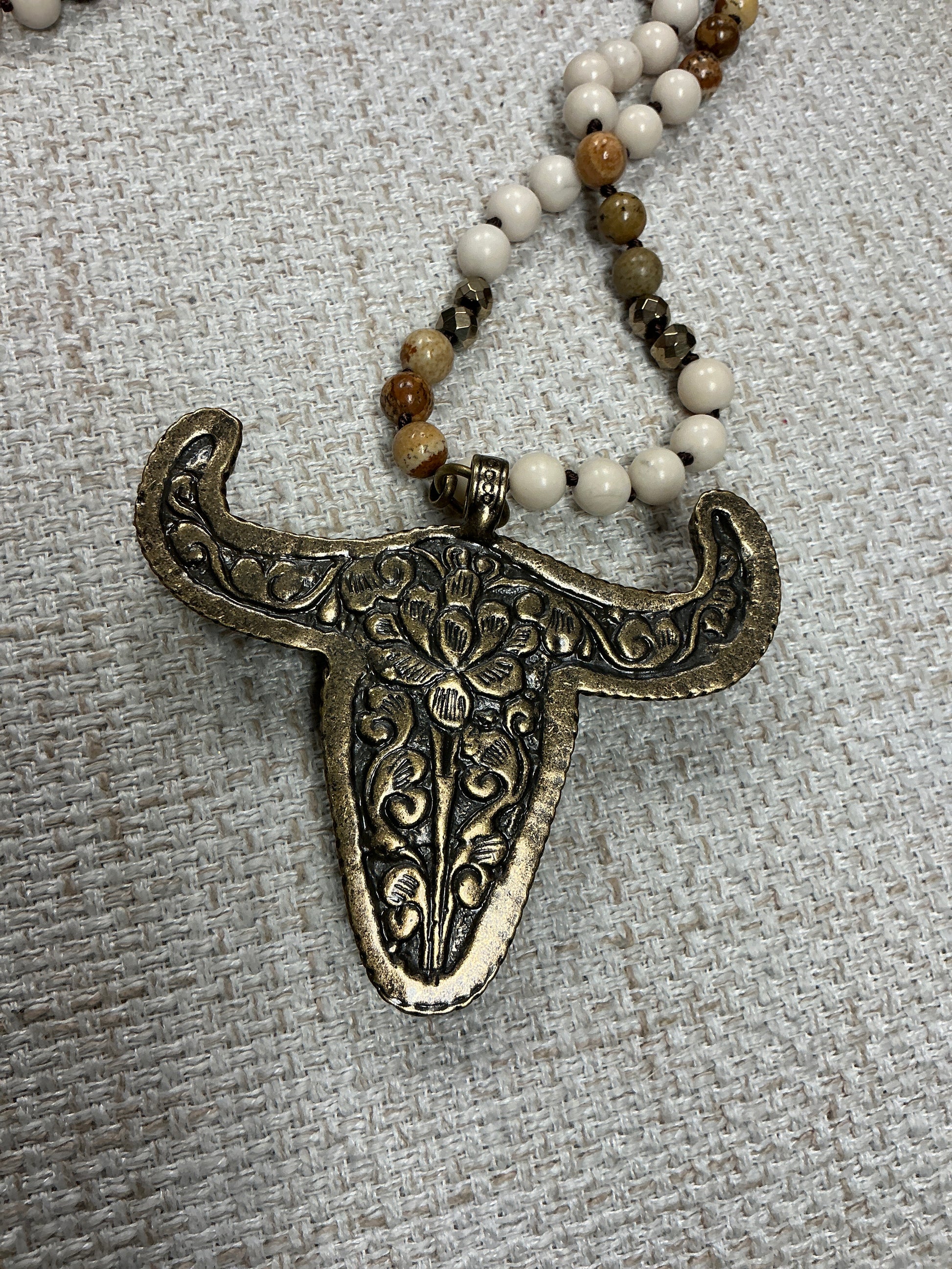 Beaded cow skull talisman necklace featuring intricate beadwork and a rustic cow skull pendant, crafted by American Unique Group.