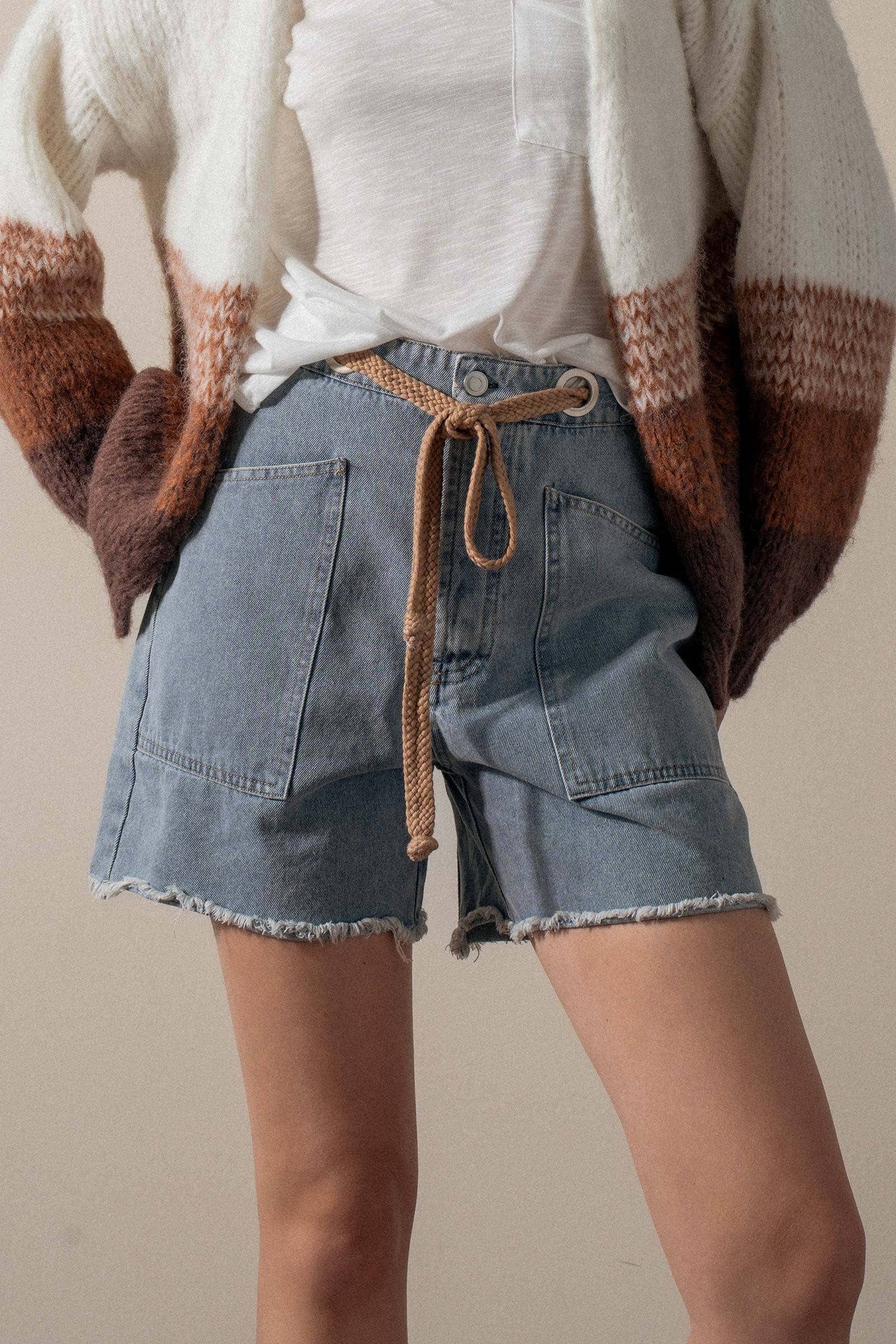 Urban Daizy high-waisted frayed hem denim shorts shown on a model, featuring distressed edges and classic blue jean fabric.