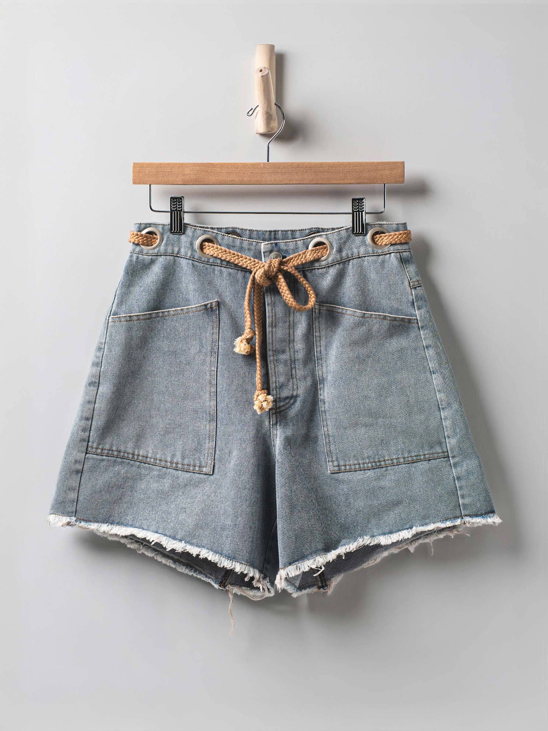 Urban Daizy high-waisted frayed hem denim shorts laid flat, showcasing distressed edges and classic blue denim fabric.