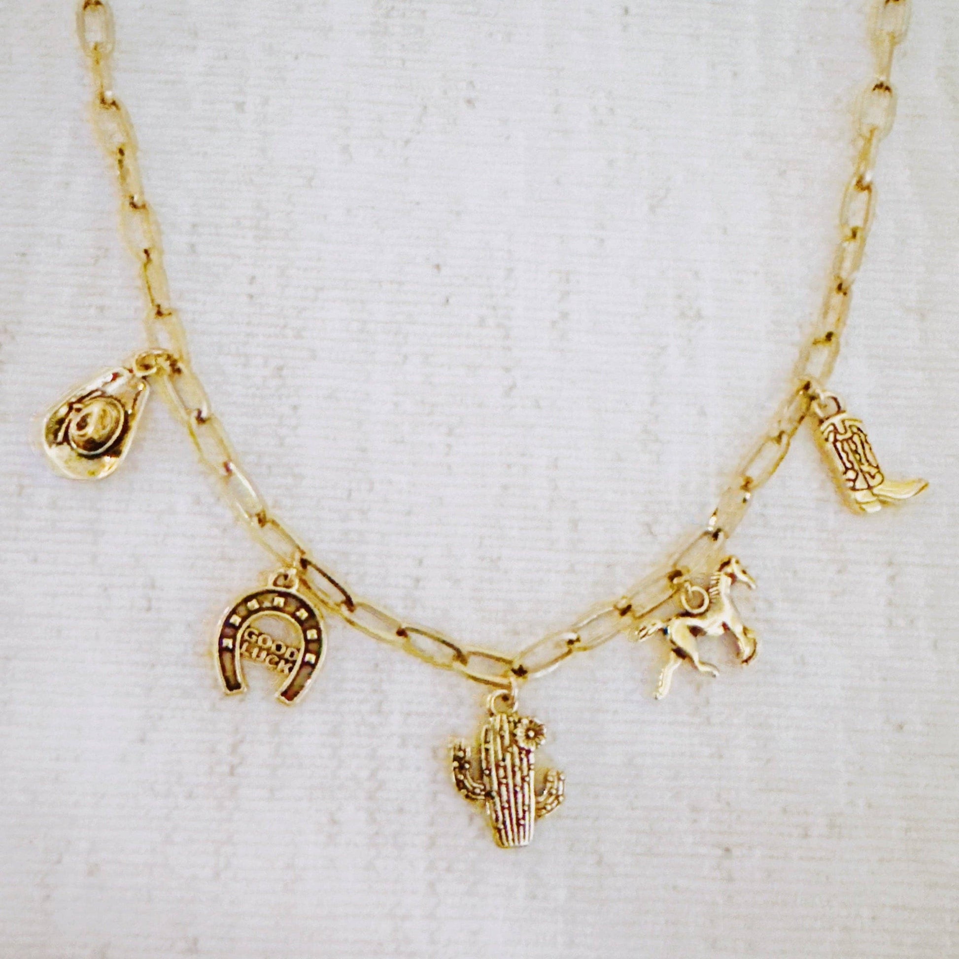 Western cowgirl charm necklace featuring cactus, horseshoe, and boot pendants by Ellison+Young, showcasing detailed jewelry design.