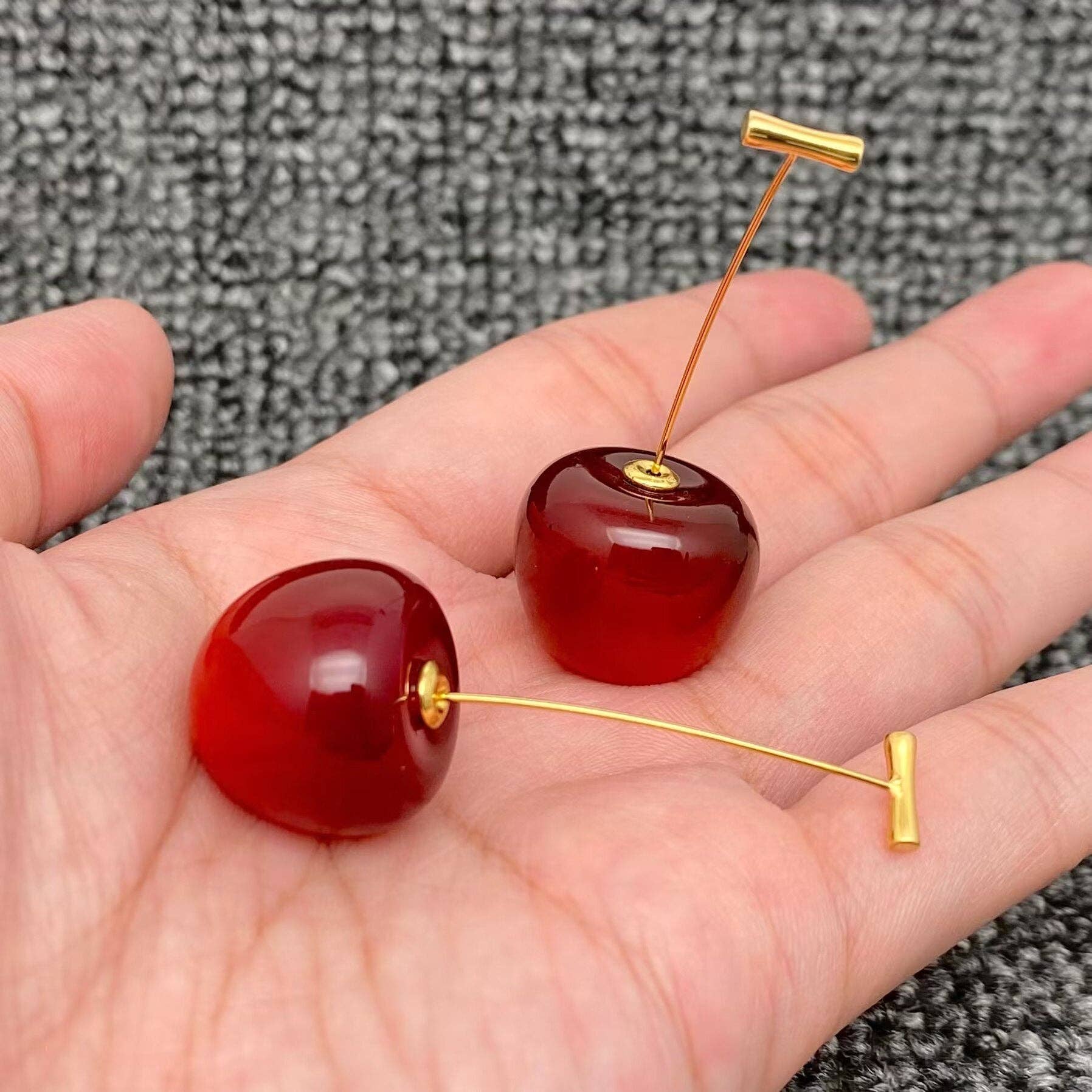 Cherry resin earrings by Mio Queena featuring vibrant red cherry-shaped resin dangle earrings with gold-tone accents.