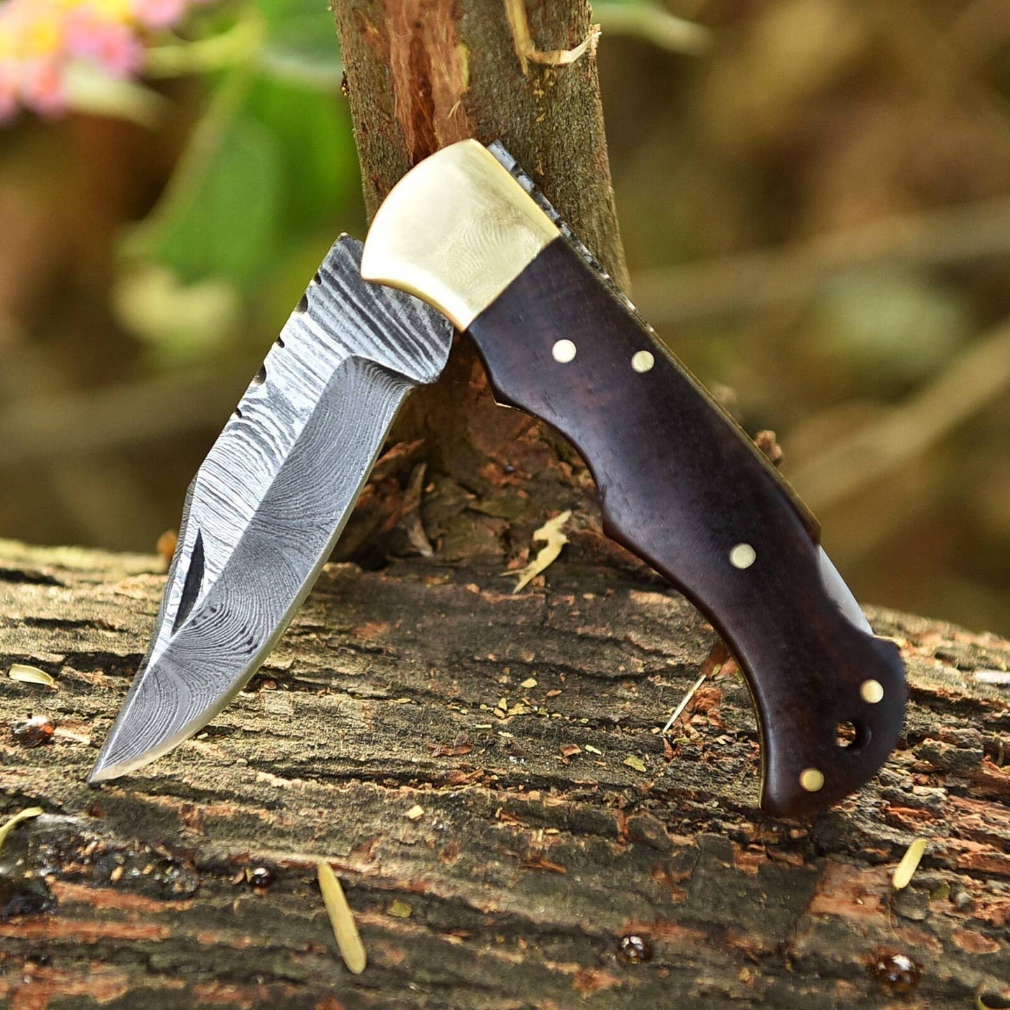 Handmade Damascus folding knife with intricate blade pattern and ergonomic handle, crafted by Liconte LLC.