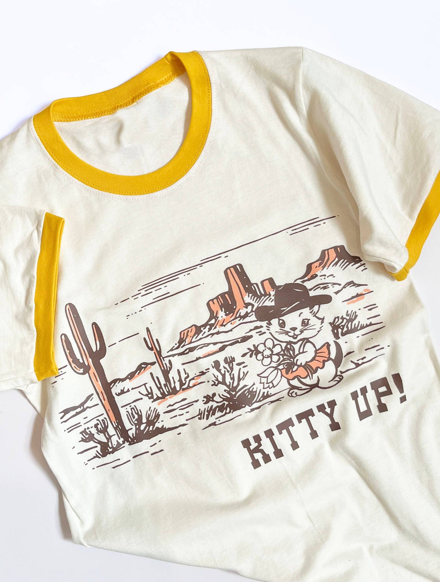 Cream yellow Kitty Up Ringer Tee shirt by The Coin Laundry featuring a funny cowboy cat design on the front.
