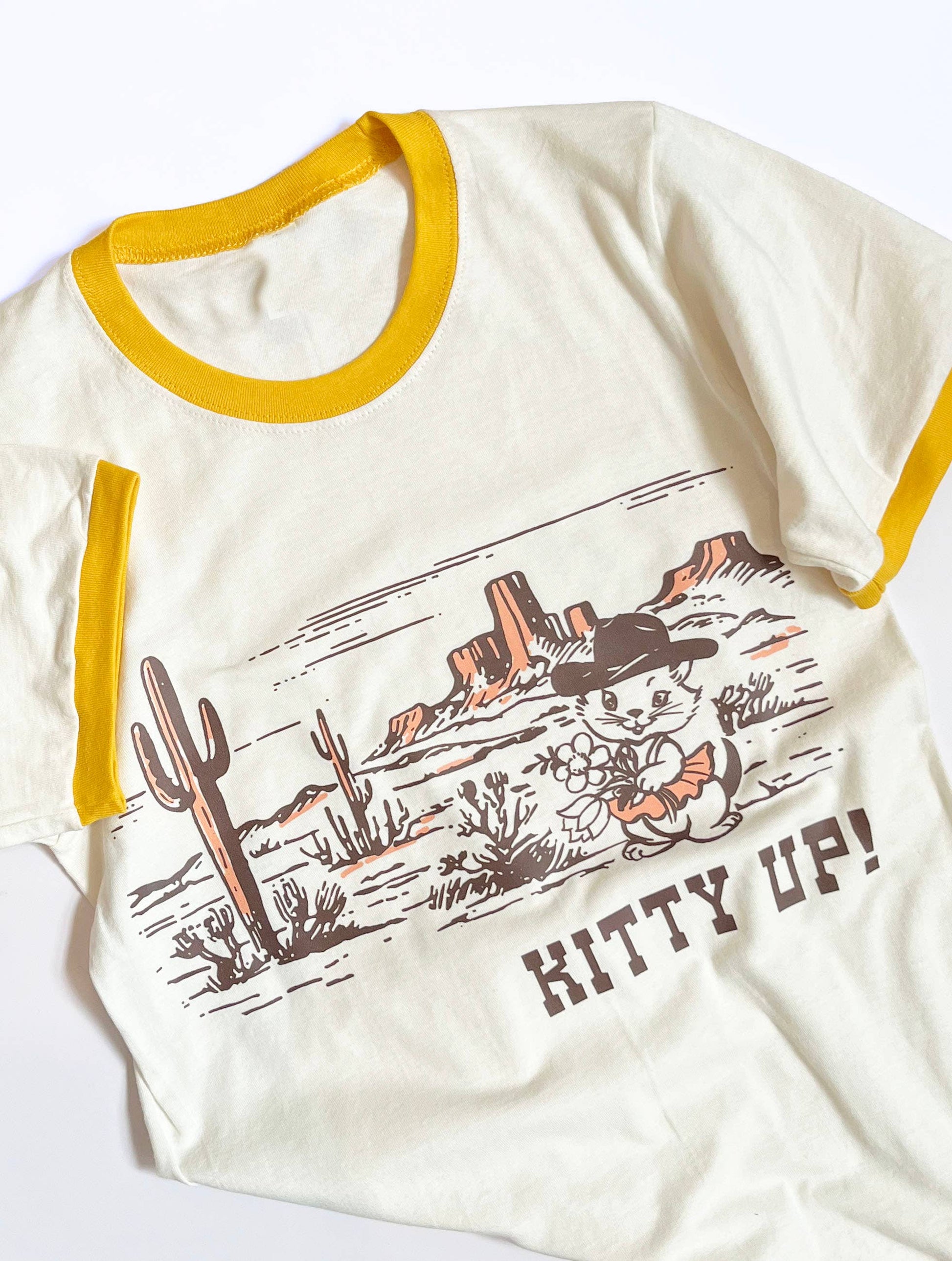 Cream yellow Kitty Up Ringer Tee shirt by The Coin Laundry featuring a funny cowboy cat design on the front.