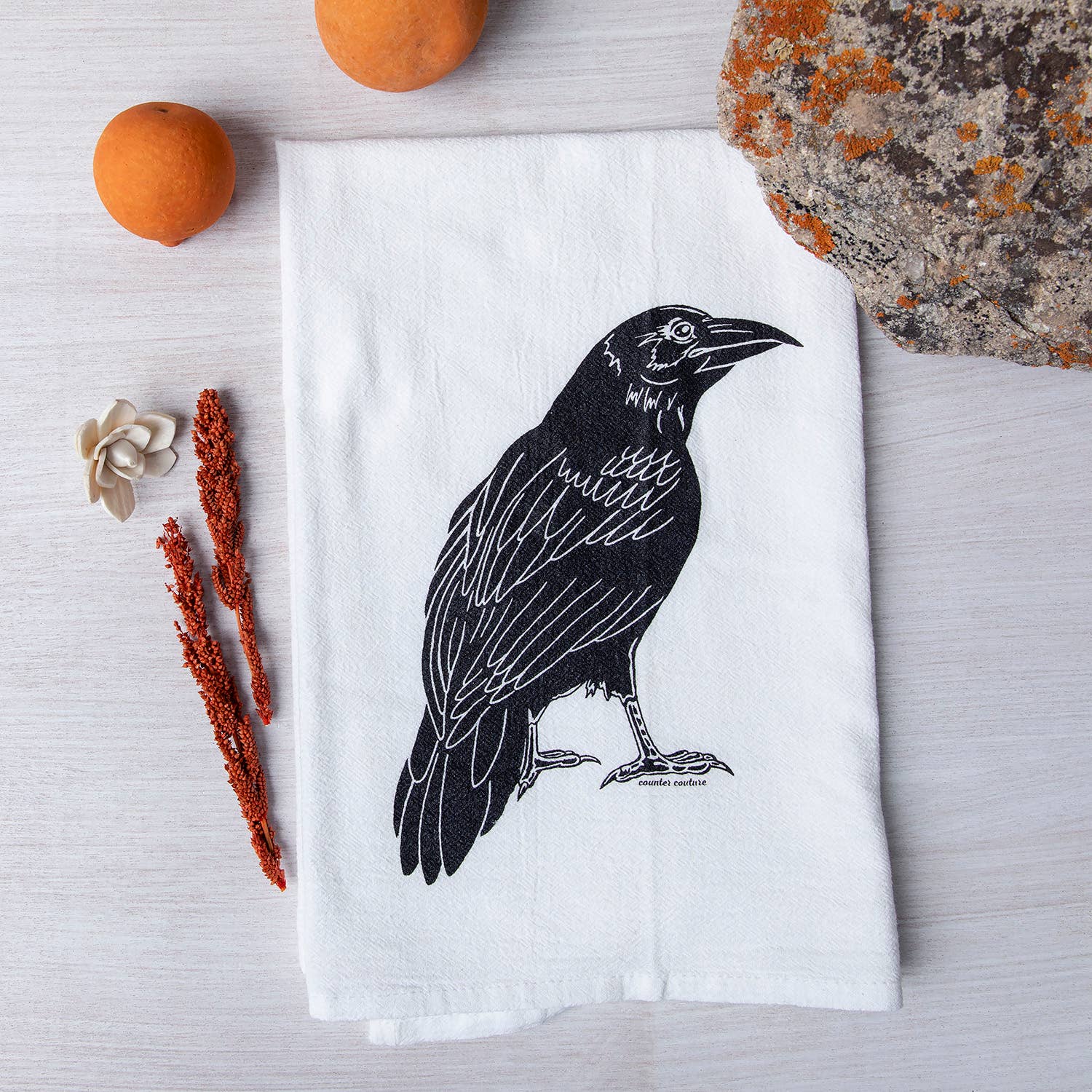Counter Couture Raven tea towel with screen-printed design, made in the USA, displayed hanging in a kitchen setting.