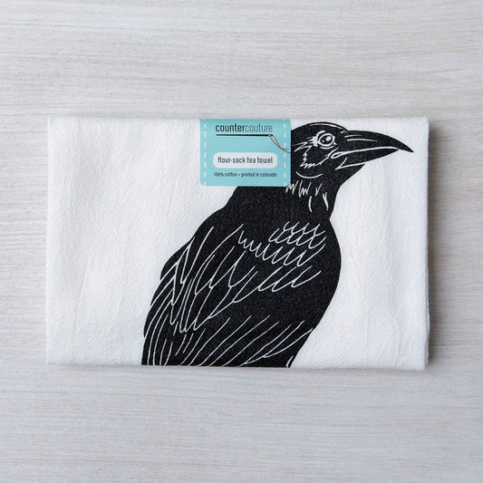 Counter Couture Raven tea towel with screen-printed design, made in USA, displayed hanging in a kitchen setting.