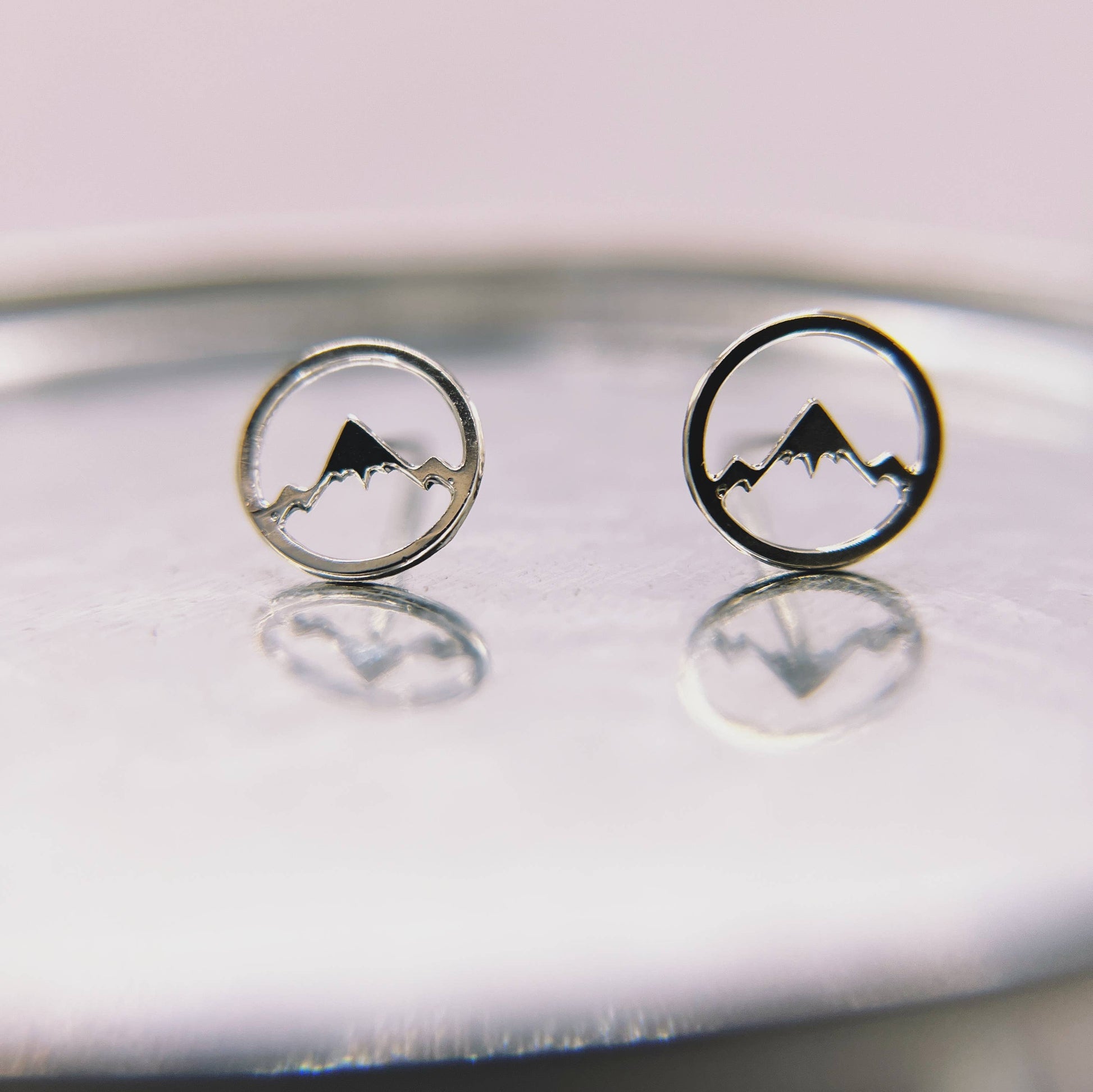 Mountainscape stud earrings by Made of Mountains featuring detailed mountain design in silver on a white background
