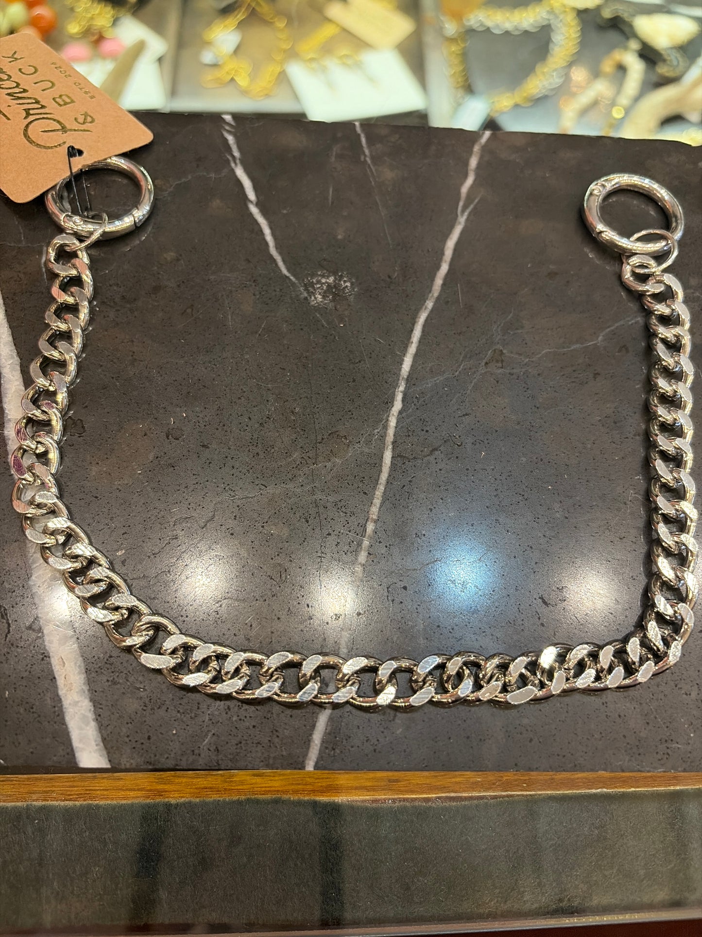 Joia bag charm chain with decorative metal accents, designed to attach to handbags for style and personalization.