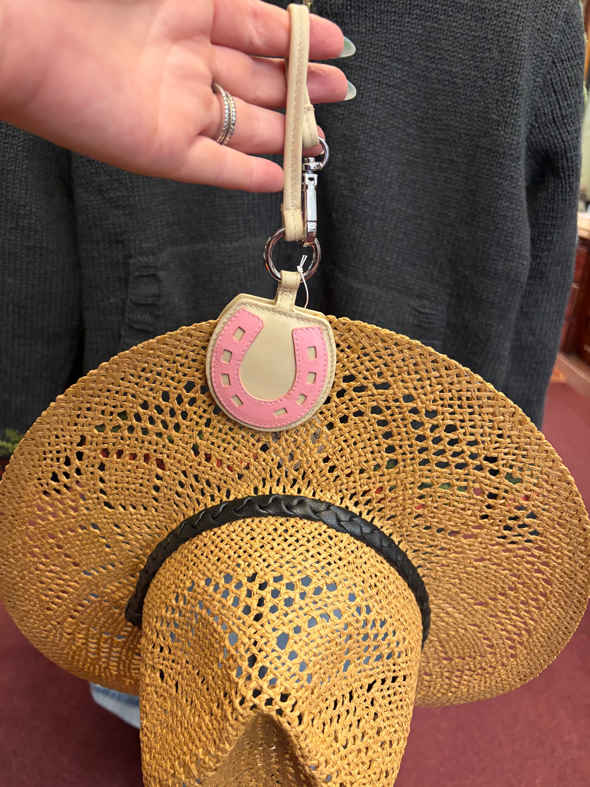 ili New York horseshoe-shaped hat holder clip attached to a wall, holding a hat in a stylish and functional design.