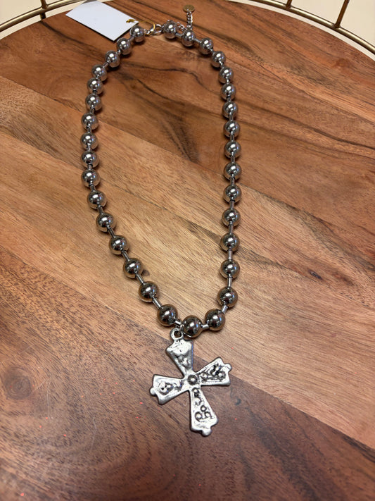 Lula 'n' Lee ball chain cross necklace hanging on a display, featuring a sleek metal cross pendant on a ball chain necklace.