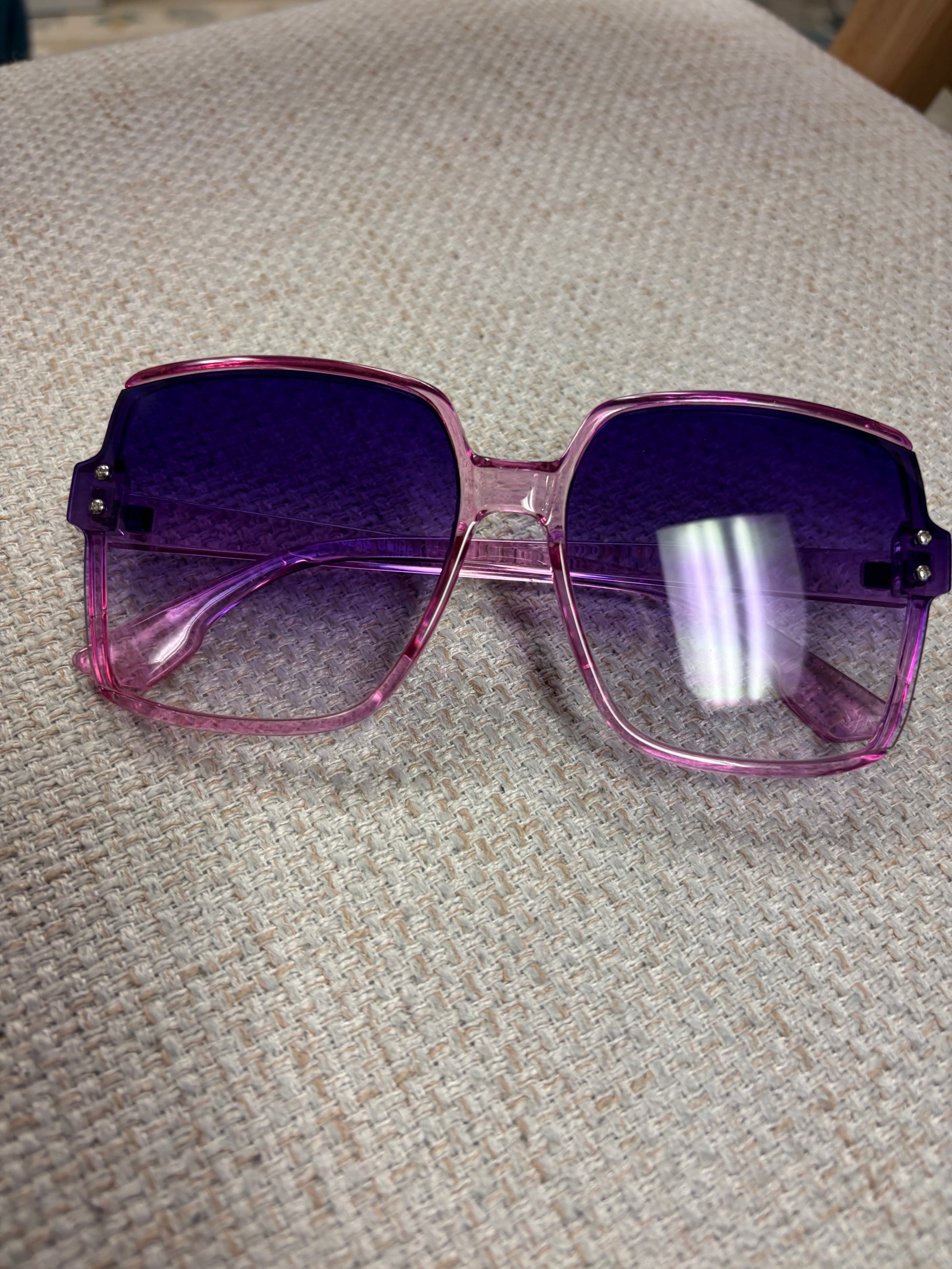 Purple Haze Sunglasses by A Sparkling Mess with purple-tinted lenses and stylish frame, displayed on a plain background.