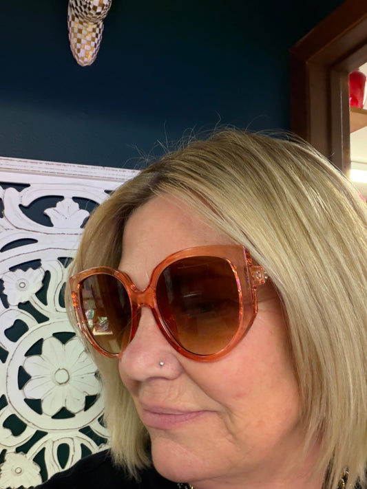 A Sparkling Mess Tangerine Dream sunglasses with orange-tinted lenses and stylish frame, shown in a close-up image.