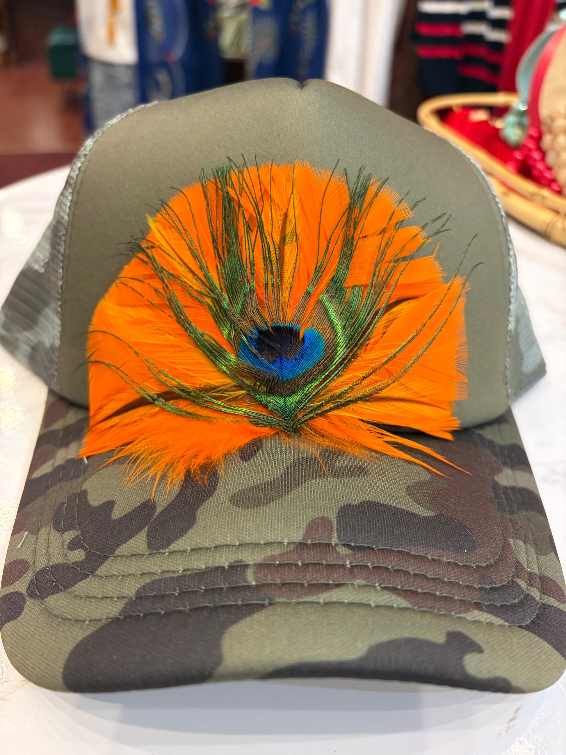 Queen Gypsy feather trucker hat with mesh back and curved brim, stylish casual accessory for outdoor wear.