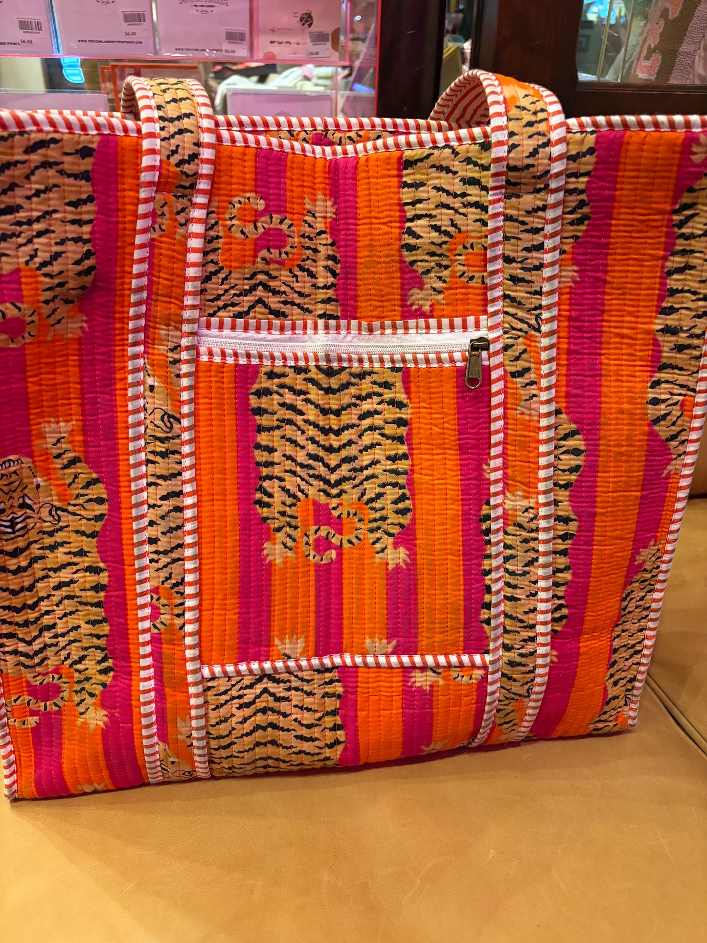 Pink and orange tiger print tote bag from The Roots, featuring a spacious design and sturdy handles.