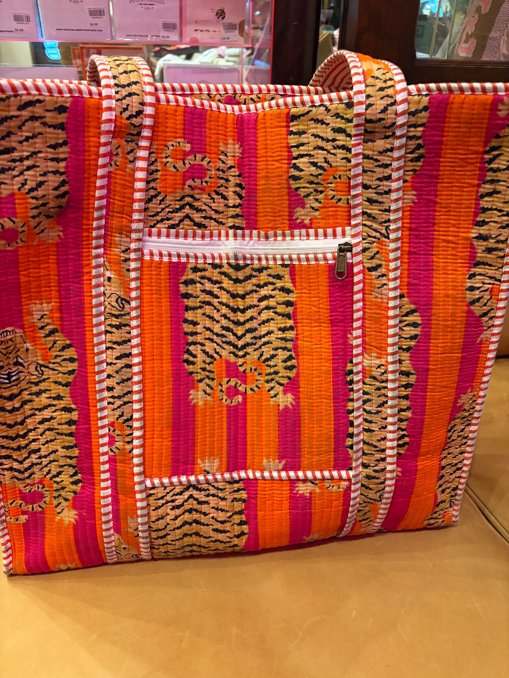 Pink and orange tiger print tote bag from The Roots, featuring a spacious design and sturdy handles.