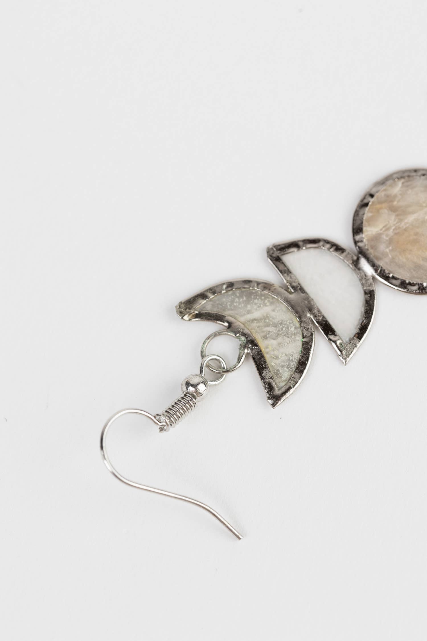 Moon phases Capiz earrings by Ten Thousand Villages, showcasing delicate shell designs hanging from silver hooks.