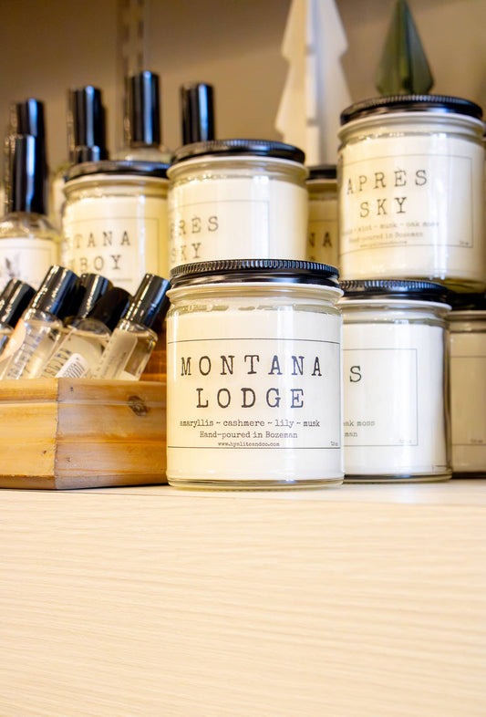 Hyalite & Co Montana Lodge candle in a rustic jar with a wooden lid, showcasing a cozy cabin scene on the label.