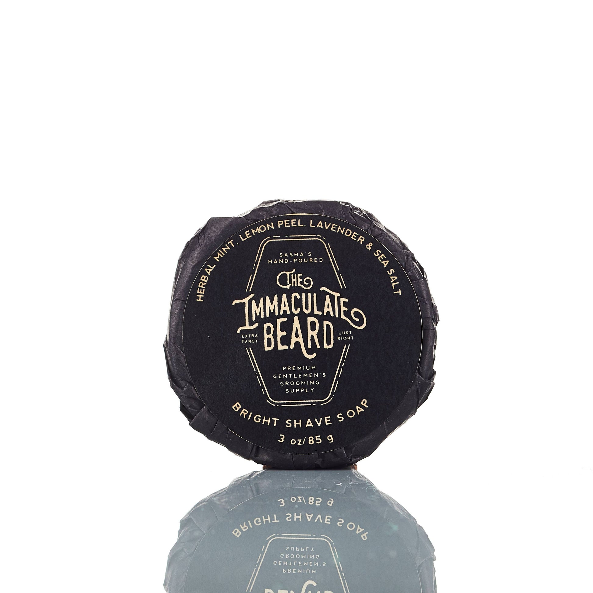 The Immaculate Beard shave soap puck in a round soap dish, showing its creamy, textured surface for a close shave.