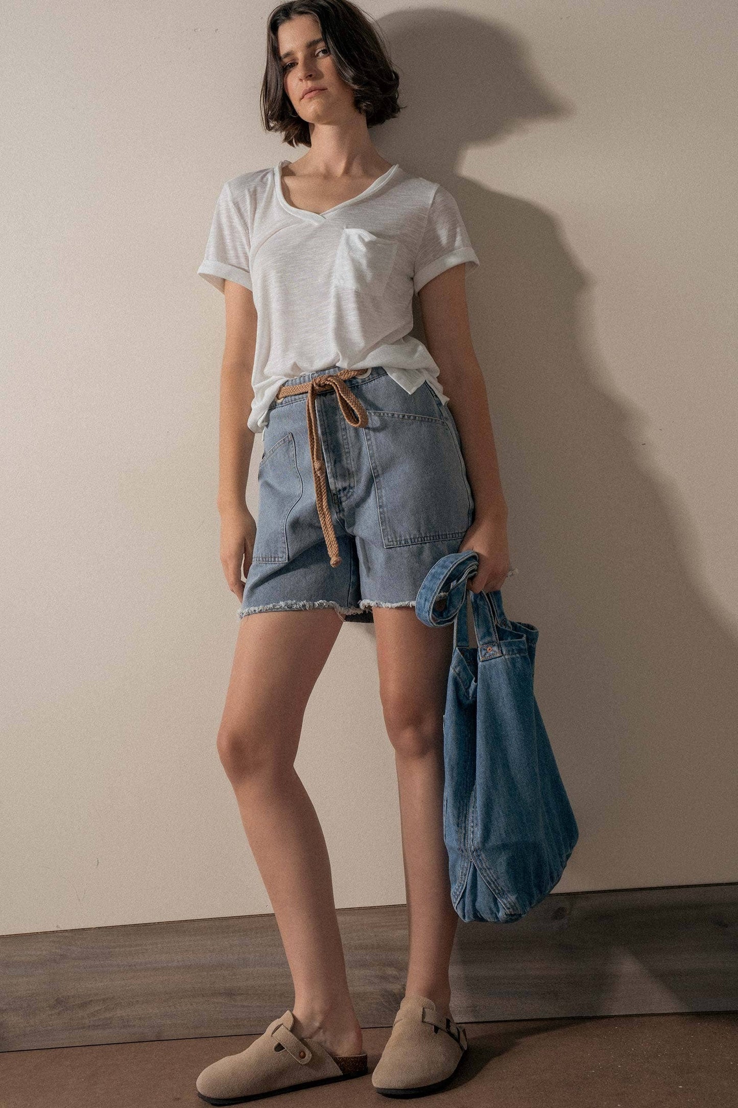 Urban Daizy high-waisted frayed hem denim shorts displayed on a model, showcasing distressed denim and stylish casual summer wear.