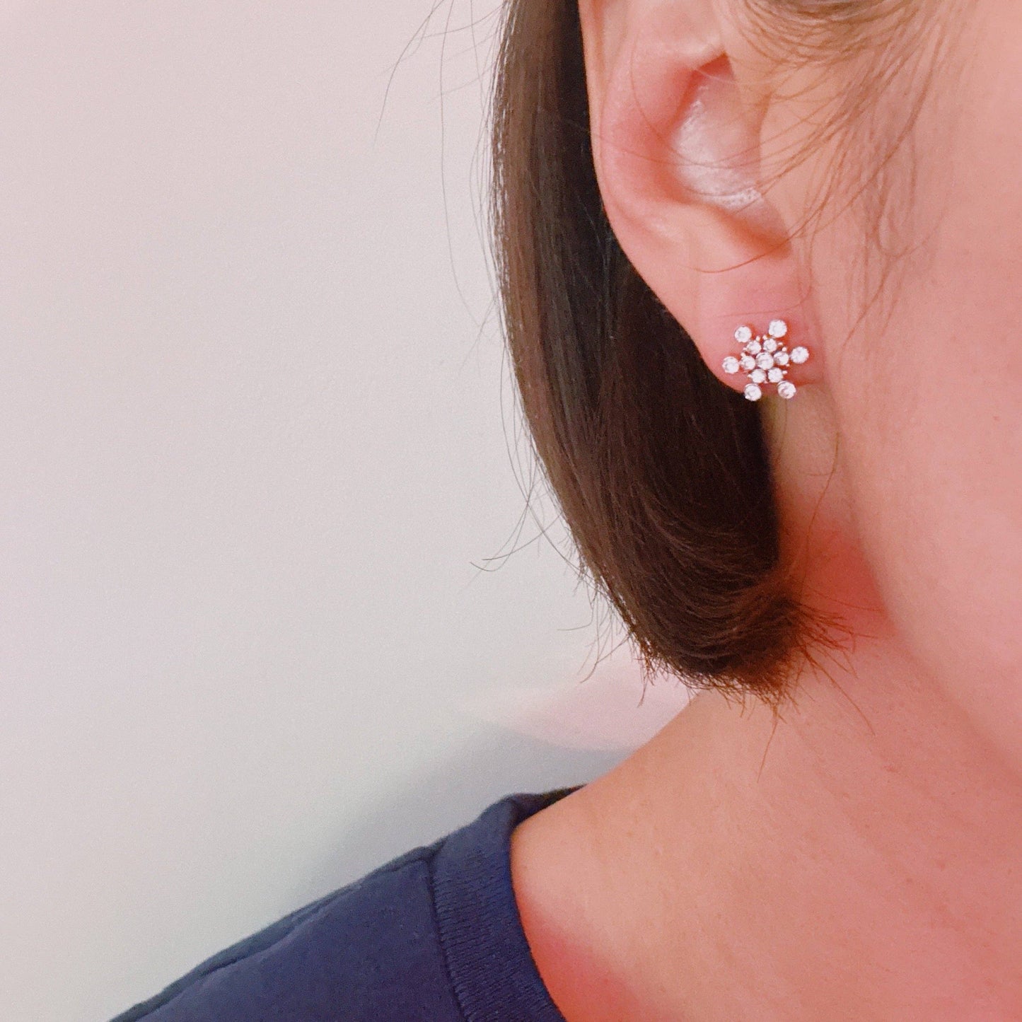 Ellison+Young snowflake stud earrings with intricate snowflake design in silver metal on a white background