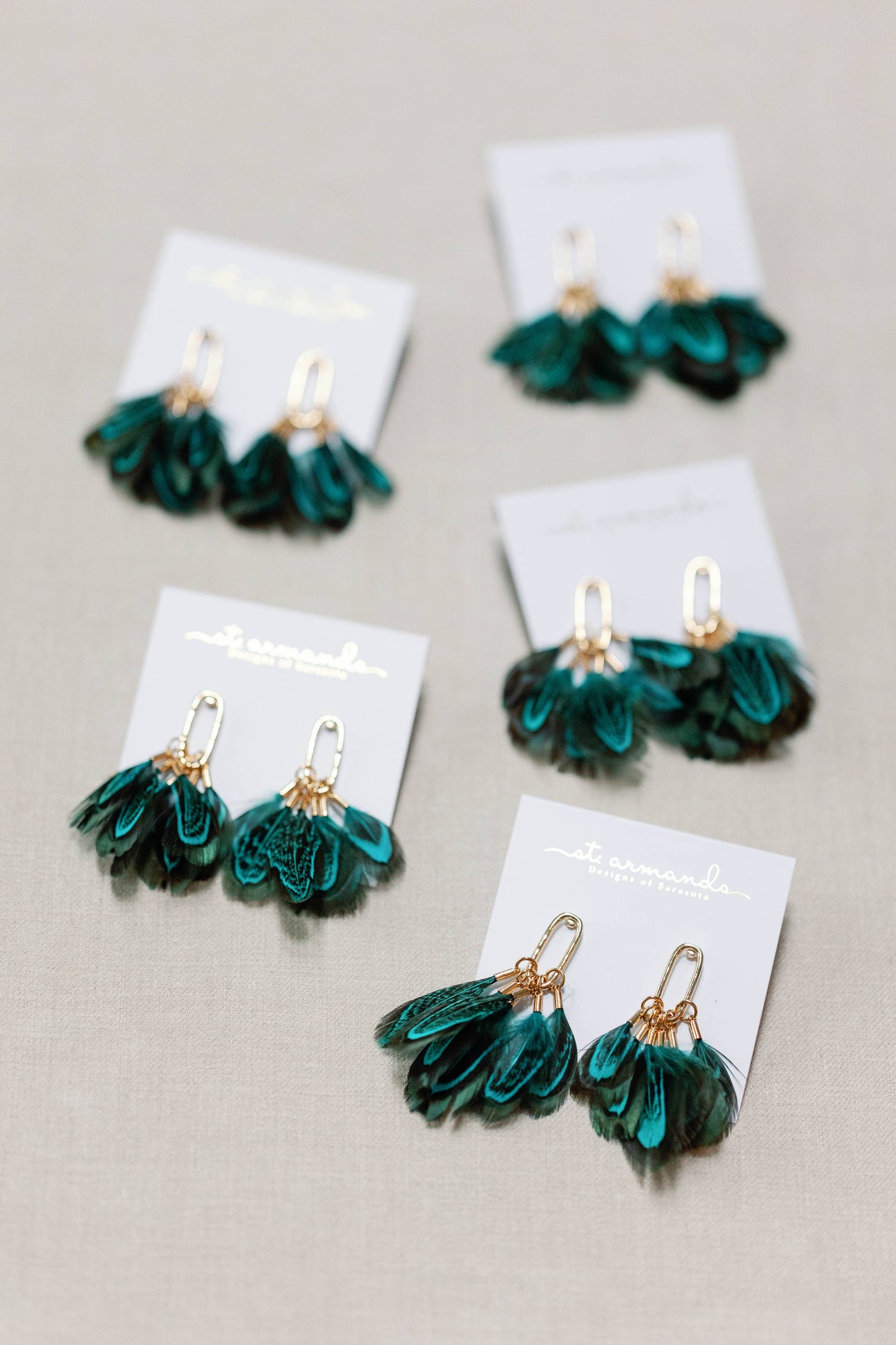 Peacock feather statement tassel earrings by St Armands Designs of Sarasota, featuring vibrant feathers and elegant dangle style.