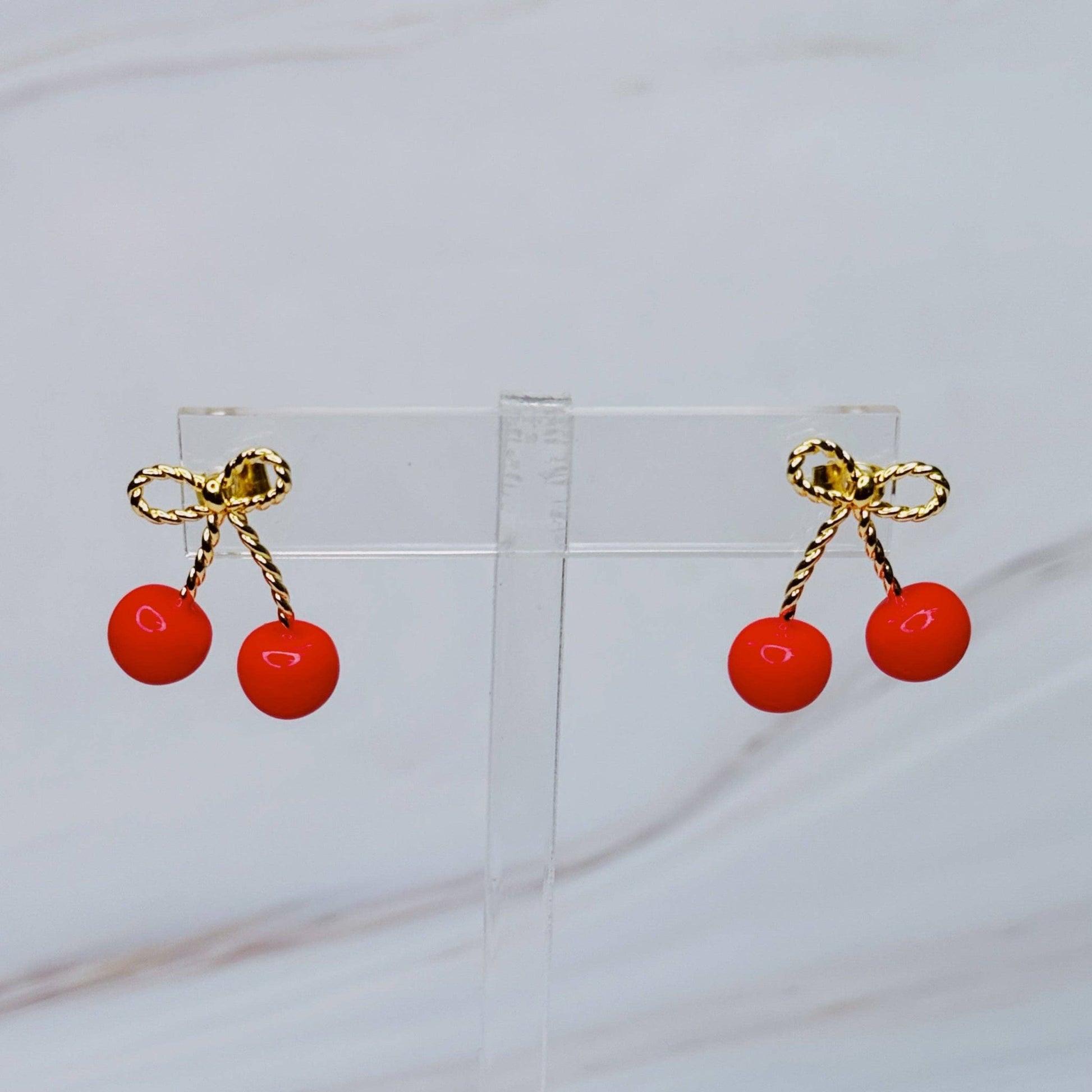 Ellison+Young bow and cherry earrings featuring delicate cherry charms and bow accents on silver hooks.