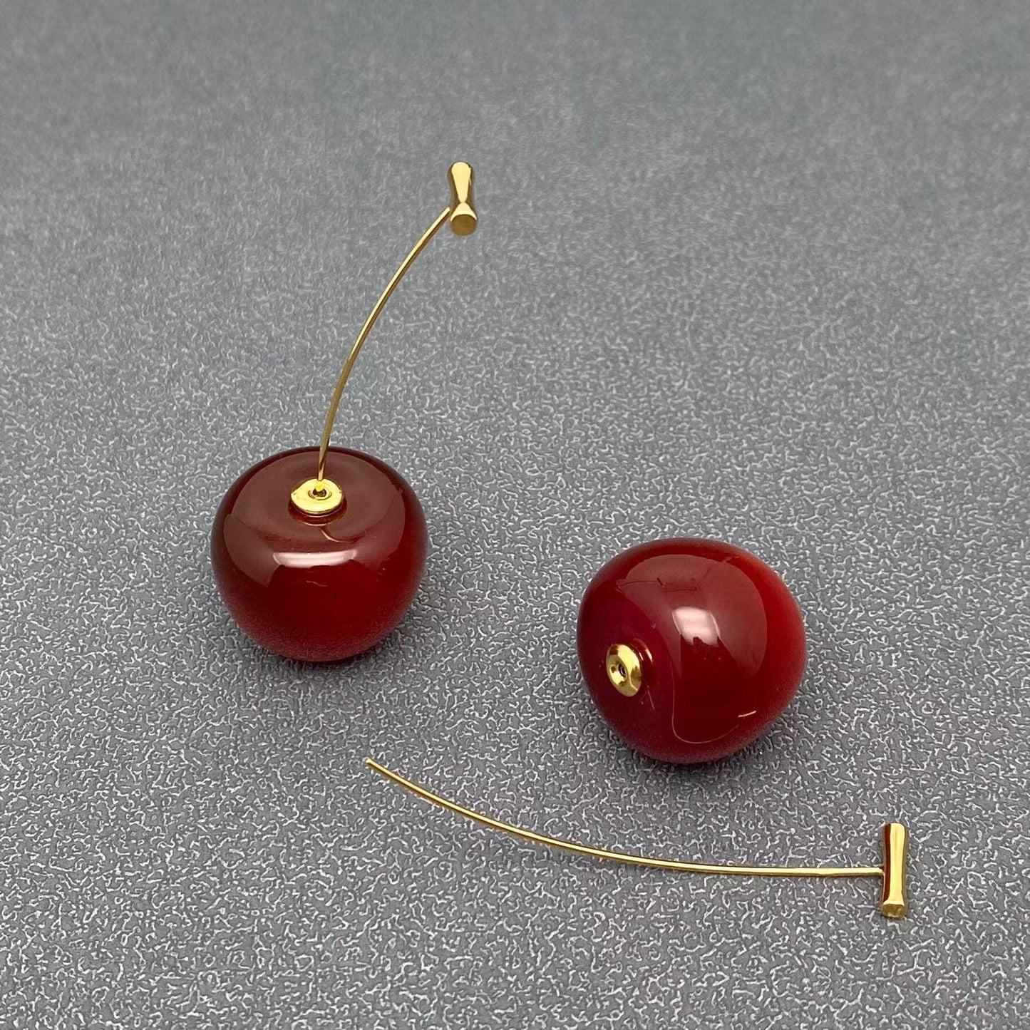 Cherry resin earrings by Mio Queena featuring vibrant red cherry-shaped resin drops and gold-tone hooks.