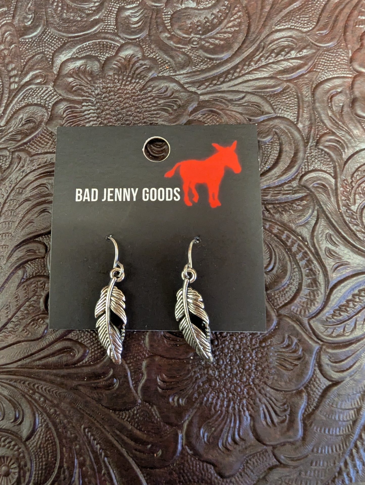 Silver feather earrings from BadAssBabe featuring lightweight, detailed feather design for boho or casual styles.