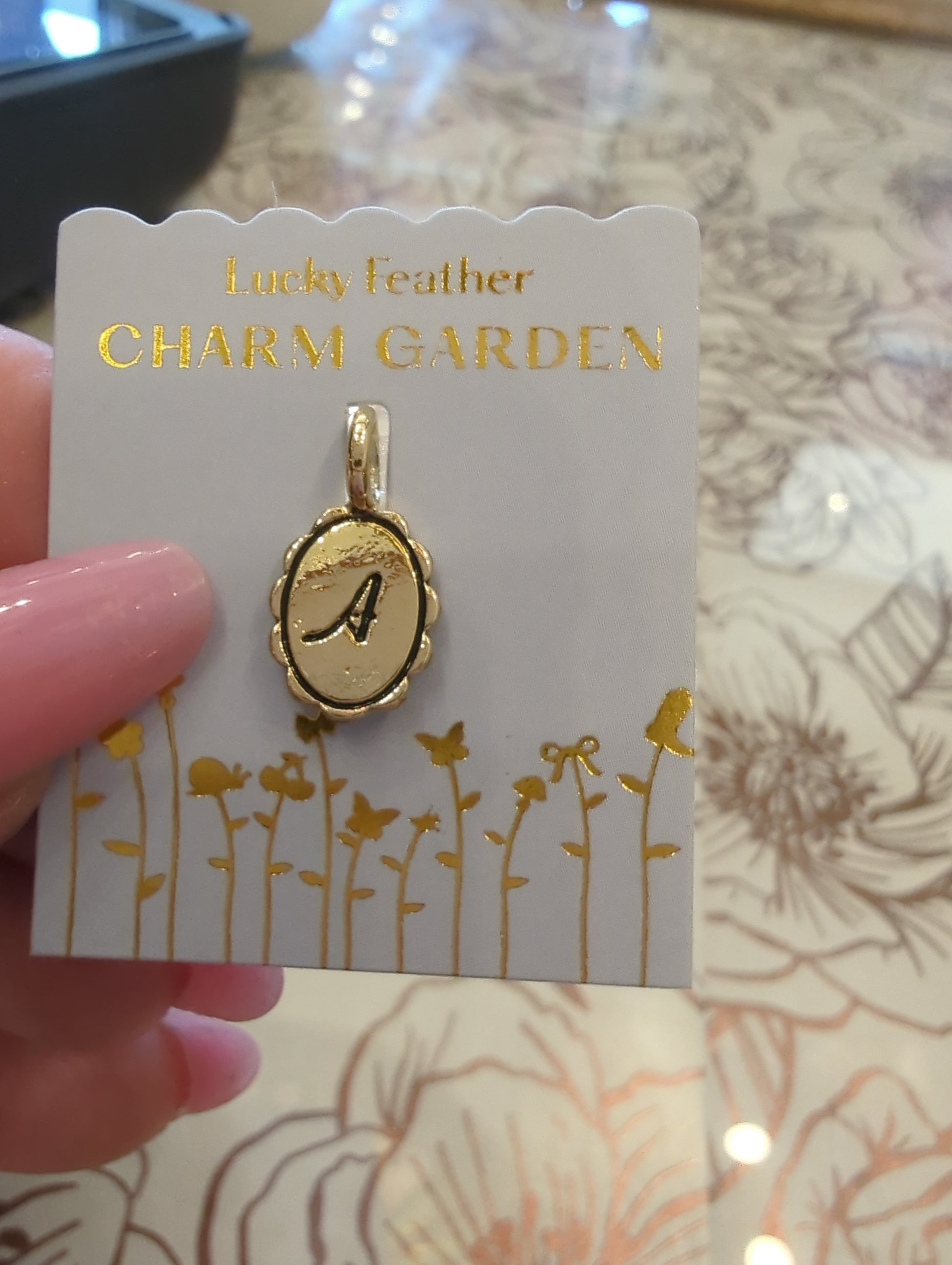 Gold initial charm with the letter A from Lucky Feather's Charm Garden collection, featuring intricate design on a silver charm.