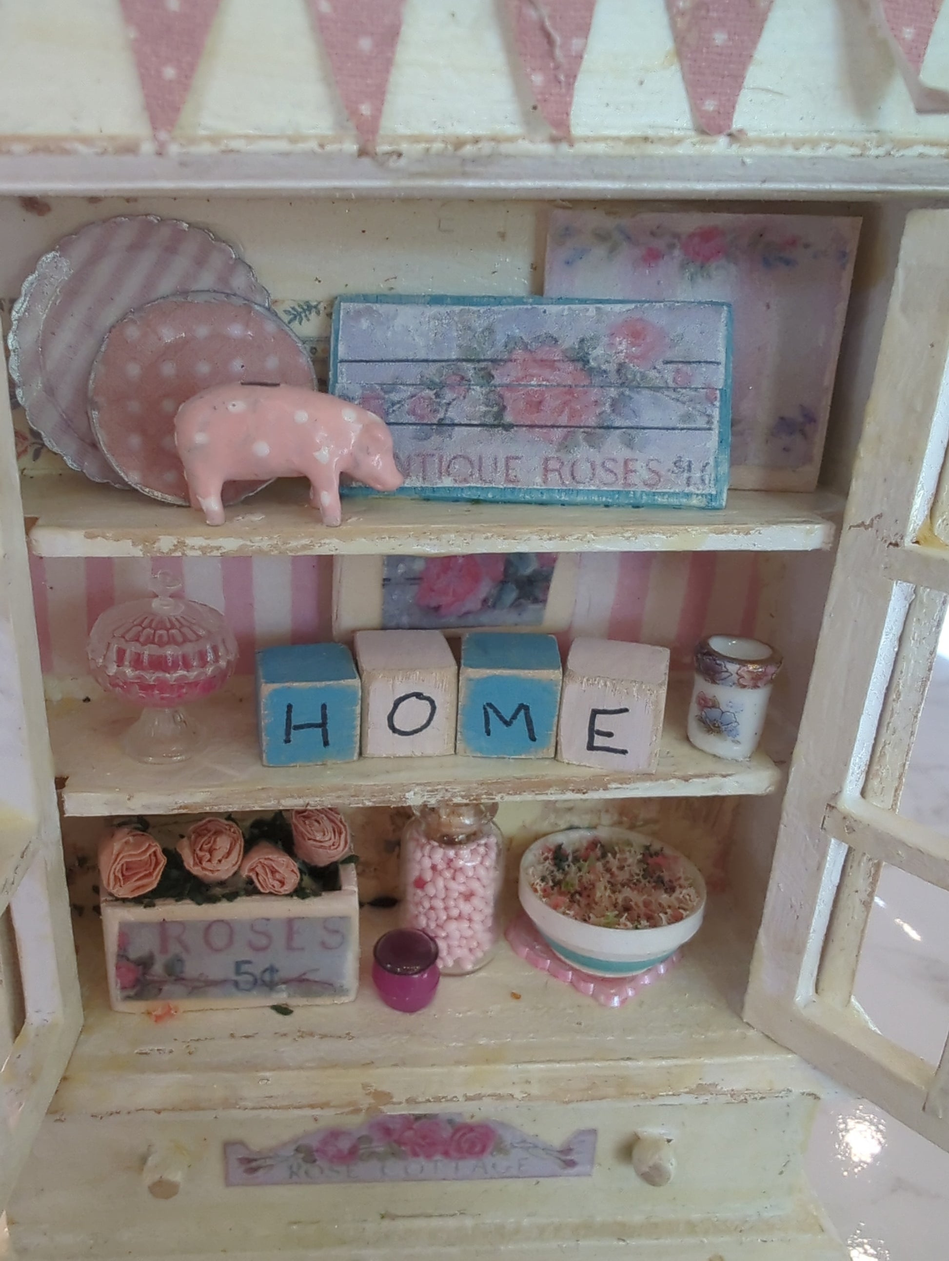 Miniature pink and white hutch scene from Detail In Miniature, featuring tiny furniture and decor in a detailed mini setting.