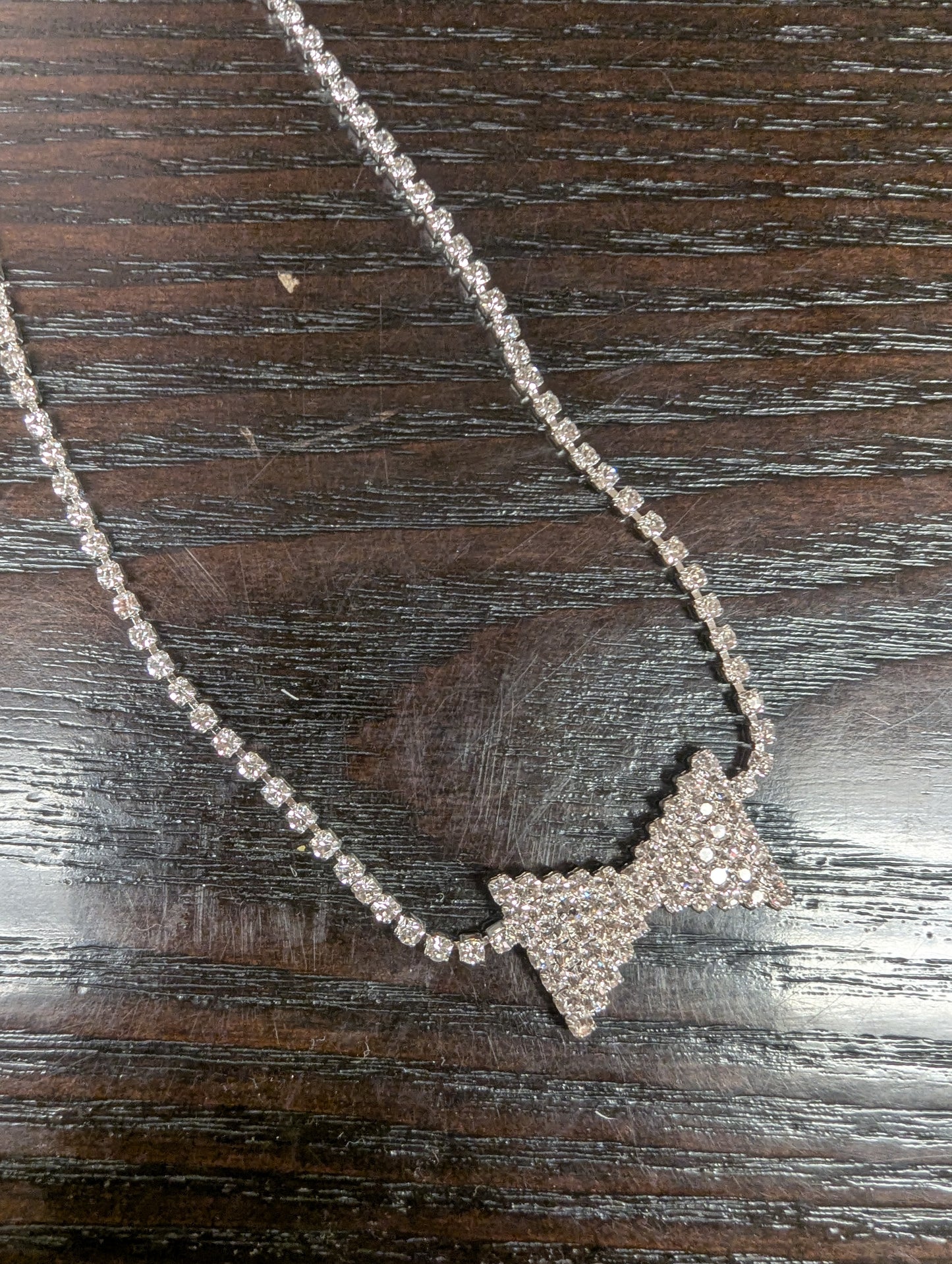 Joia bowtie choker necklace featuring a delicate black ribbon bow and sleek silver chain on a neutral background.