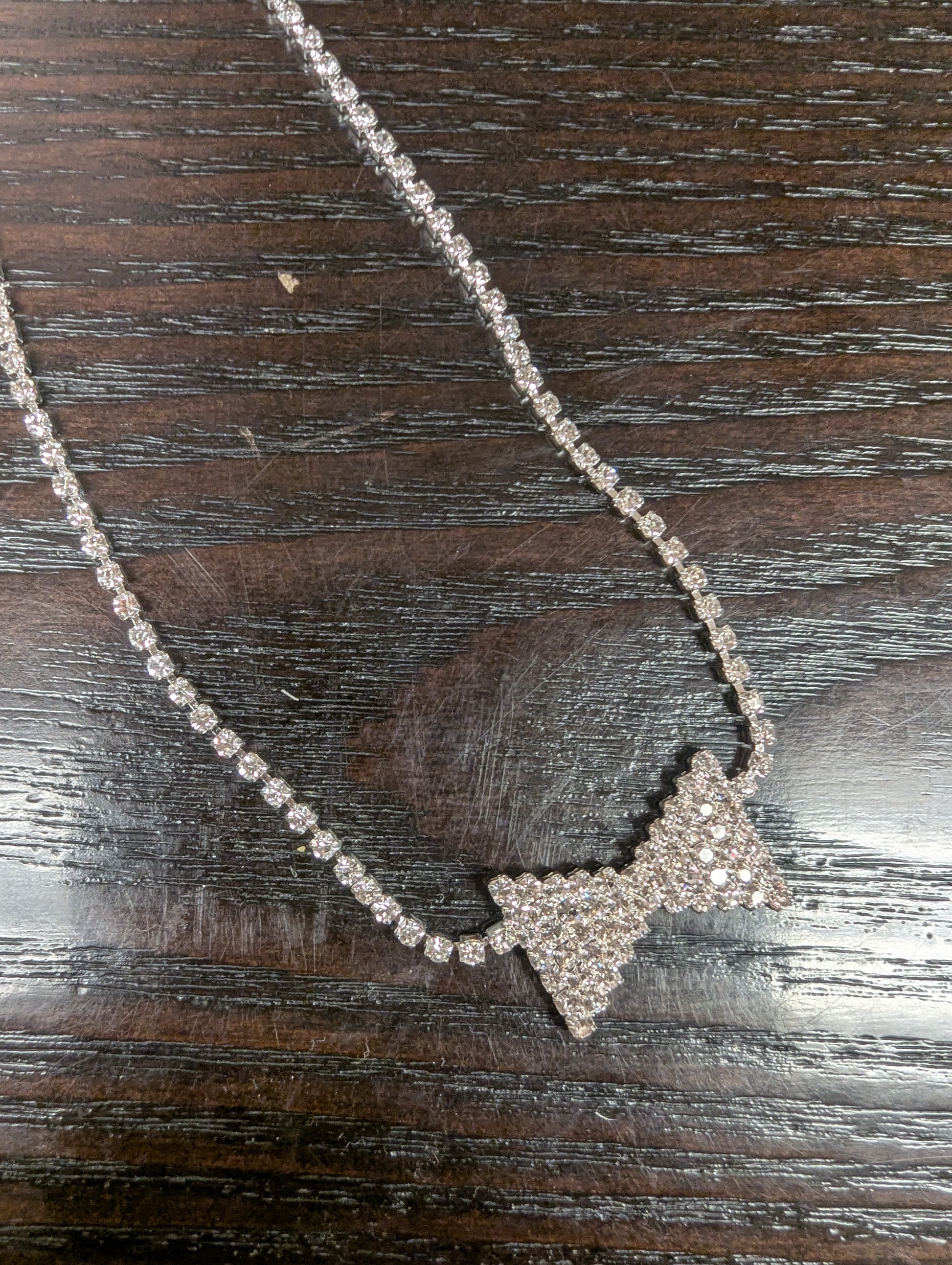 Joia bowtie choker necklace featuring a delicate black ribbon bow and sleek silver chain on a neutral background.