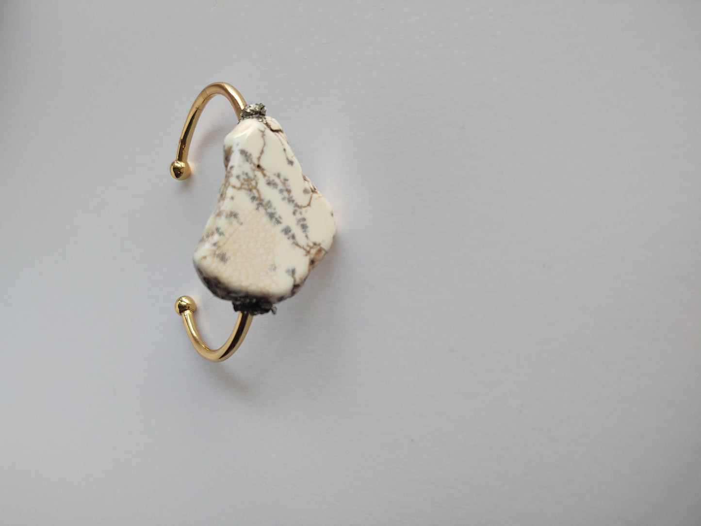 A Howlite cuff bracelet from A Sparkling Mess featuring smooth, white marbled stones and a sleek, open design.